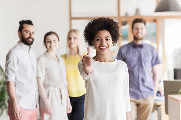 Image showing woman showing thumbs up over creative office team