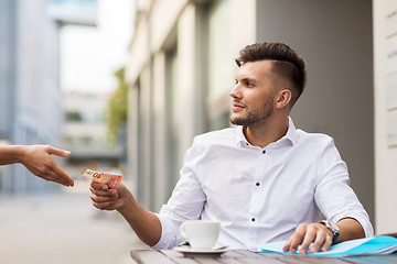 Image showing man with euro money paying for coffee at cafe