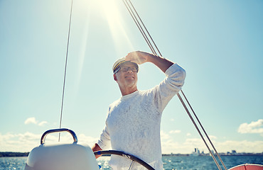 Image showing senior man at helm on boat or yacht sailing in sea