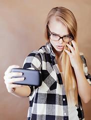 Image showing young pretty blond hipster girl making selfie on warm brown background, lifestyle people concept