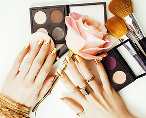 Image showing woman hands with golden manicure and many rings holding brushes,