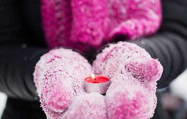 Image showing close up of hands in winter mittens holding candle