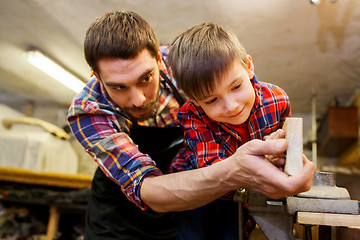 Image showing father and little son with wood plank at workshop