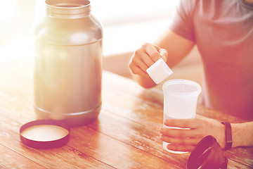 Image showing close up of man with protein shake bottle and jar