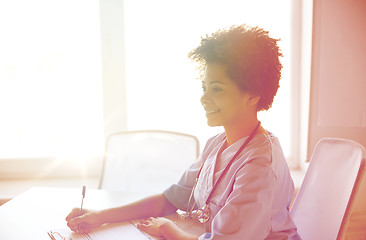 Image showing happy female doctor or nurse writing at hospital