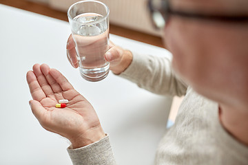 Image showing close up of old man hands with pills and water