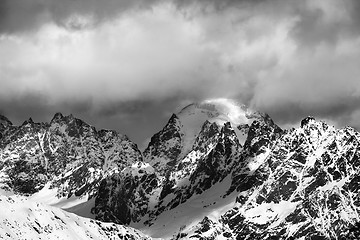 Image showing Black and white snow mountains in clouds at sunny winter day