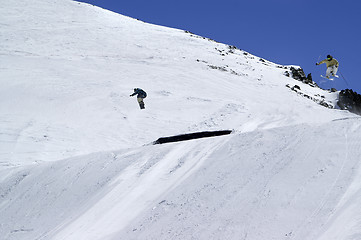 Image showing Snowboarder and skier jumping in snow park at ski resort on sunn