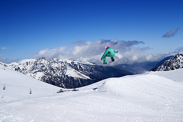 Image showing Snowboarder jumping in snow park at winter mountain on nice sunn