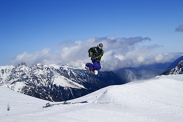 Image showing Snowboarder jumping in terrain park at snow mountain on sunny wi