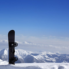 Image showing Snowboard in snow near off-piste slope in sun day