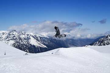 Image showing Snowboarder jumping in snow mountains at sun winter day