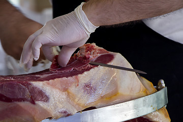 Image showing Man slicing prosciutto famous and tasty mediterranean delicatess