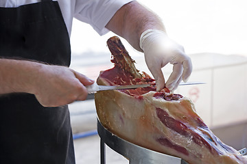 Image showing Man slicing prosciutto famous and tasty mediterranean delicatess
