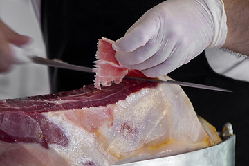 Image showing Man slicing prosciutto famous and tasty mediterranean delicatess