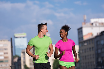 Image showing young smiling multiethnic couple jogging in the city