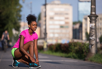 Image showing African american woman runner tightening shoe lace