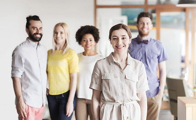 Image showing happy young woman over creative team in office