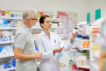 Image showing pharmacist and senior man buying drug at pharmacy