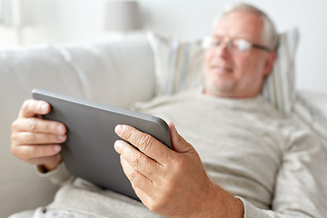 Image showing senior man with tablet pc lying on sofa at home