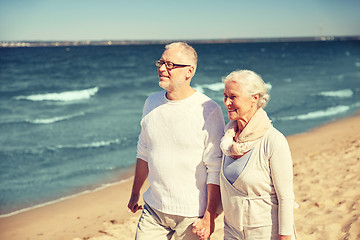 Image showing happy senior couple walking along summer beach