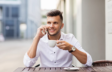 Image showing man with coffee calling on smartphone at city cafe