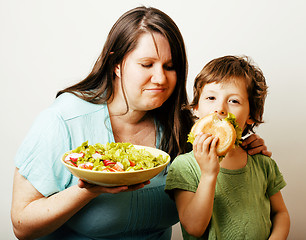 Image showing mature woman holding salad and little cute boy with hamburger te