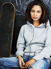 Image showing young cute teenage girl in classroom at blackboard seating on ta