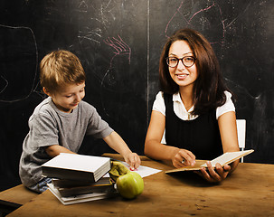 Image showing little cute boy with young teacher in classroom studying at blac