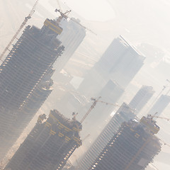 Image showing Skyscrappers construction site with cranes on top of buildings.