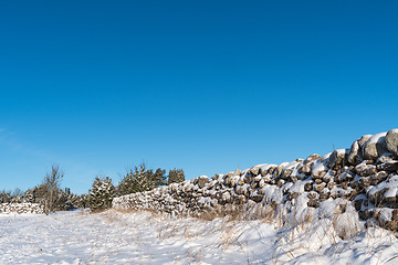 Image showing Snow covered stone wall from a low perspective