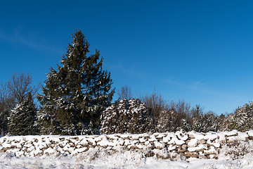 Image showing Snow covered stone wall and a blue sky