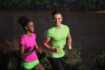 Image showing young smiling multiethnic couple jogging in the city