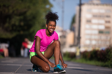 Image showing African american woman runner tightening shoe lace