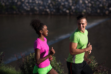 Image showing young smiling multiethnic couple jogging in the city