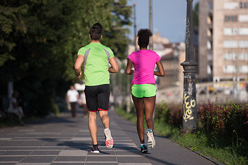 Image showing young smiling multiethnic couple jogging in the city