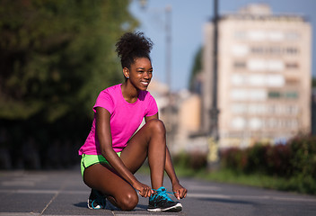 Image showing African american woman runner tightening shoe lace