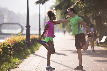 Image showing jogging couple warming up and stretching in the city