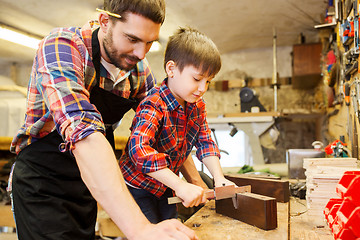 Image showing boy and dad with calipers measure wood at workshop