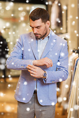 Image showing young man trying jacket on in clothing store