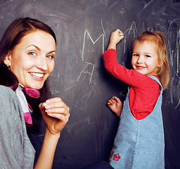 Image showing cute cheerful teacher with little pupil in classroom at blackboard learning, happy smiling, lfestyle people concept