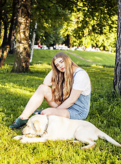 Image showing young attractive blond woman playing with her dog in green park 