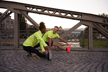 Image showing jogging couple warming up and stretching in the city