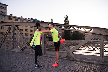 Image showing jogging couple warming up and stretching in the city