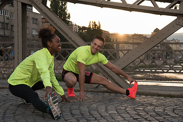 Image showing jogging couple warming up and stretching in the city