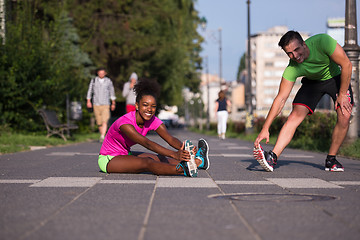 Image showing jogging couple warming up and stretching in the city