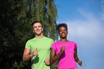 Image showing young smiling multiethnic couple jogging in the city