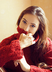 Image showing young pretty real woman in red sweater and scarf all over her fa