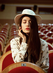 Image showing portrait of a pretty girl hipster in a movie theater wearing hat, dreaming alone