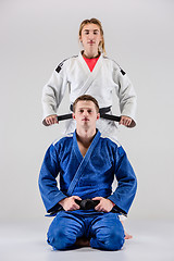 Image showing The two judokas fighters posing on gray